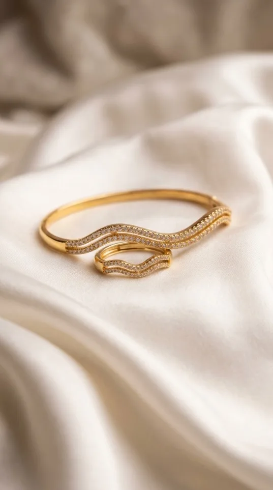 Gold zigzag bangle and ring set with crystal stone clusters on satin fabric