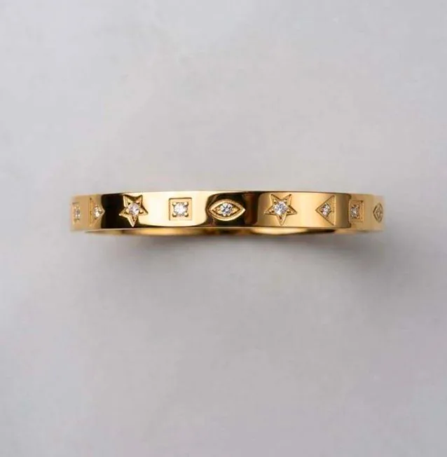 Gold-tone bangle bracelet with star, evil eye, and CZ charm details