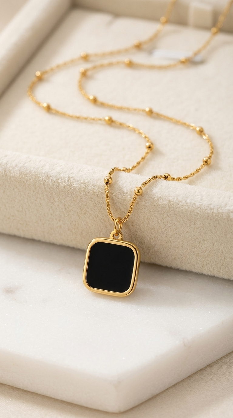 Gold satellite chain necklace with a black enamel square pendant