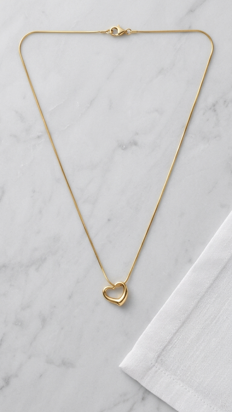 Minimal gold chain necklace with heart-shaped pendant on satin fabric, elegant everyday jewelry for women