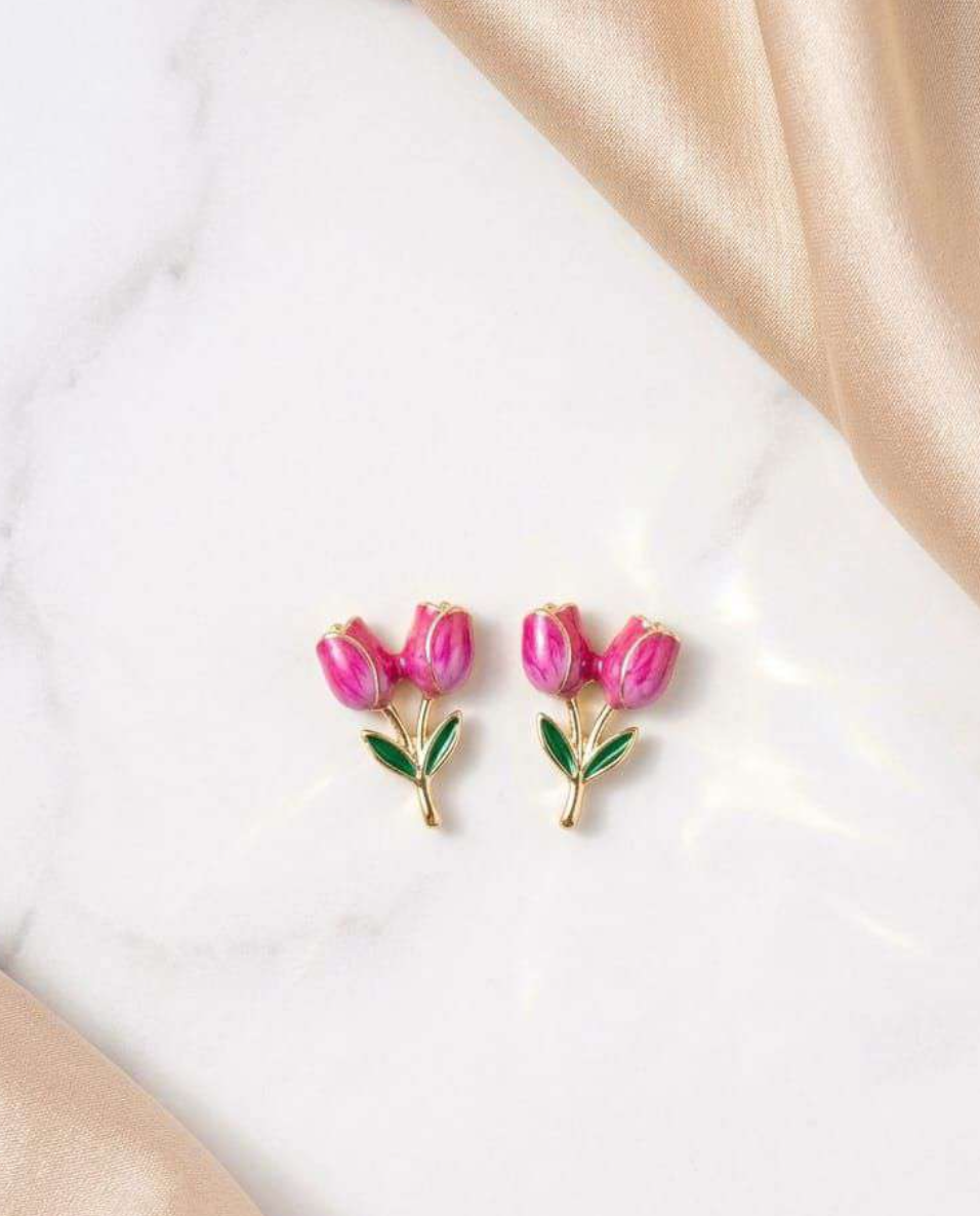 Gold-tone pink enamel tulip stud earrings with green leaves on marble background