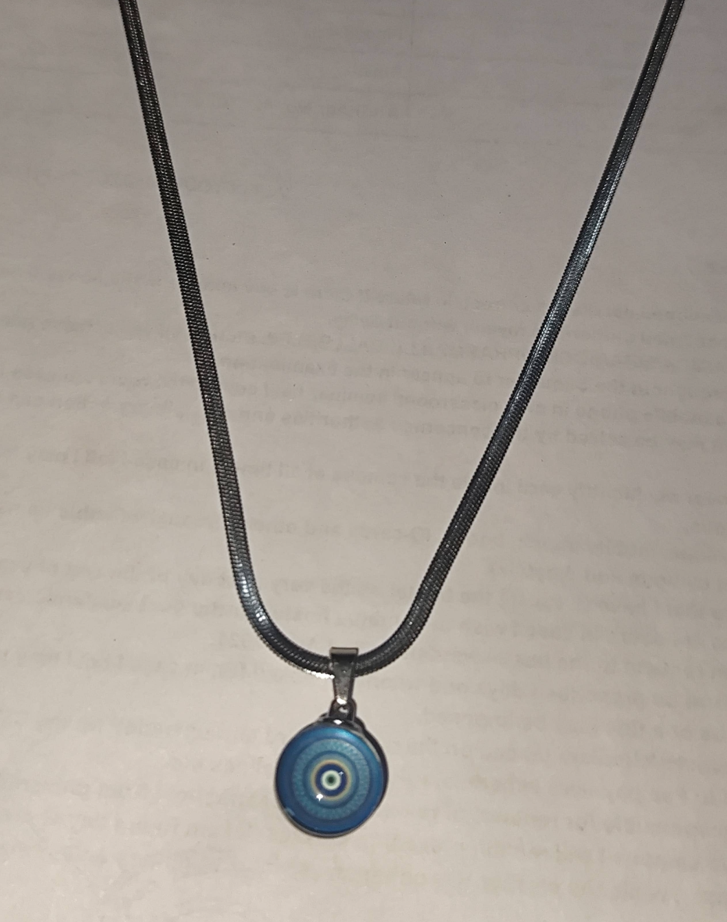 Silver herringbone chain necklace with round blue evil eye pendant