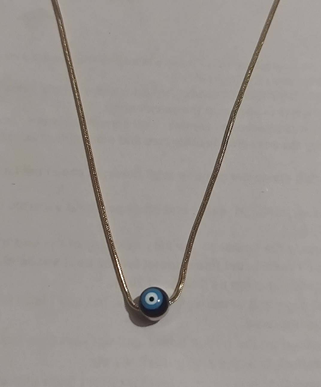 Gold snake chain necklace with single blue evil eye glass bead