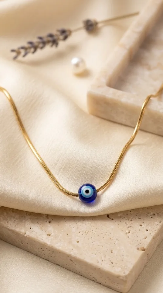 Gold snake chain necklace with single blue evil eye glass bead