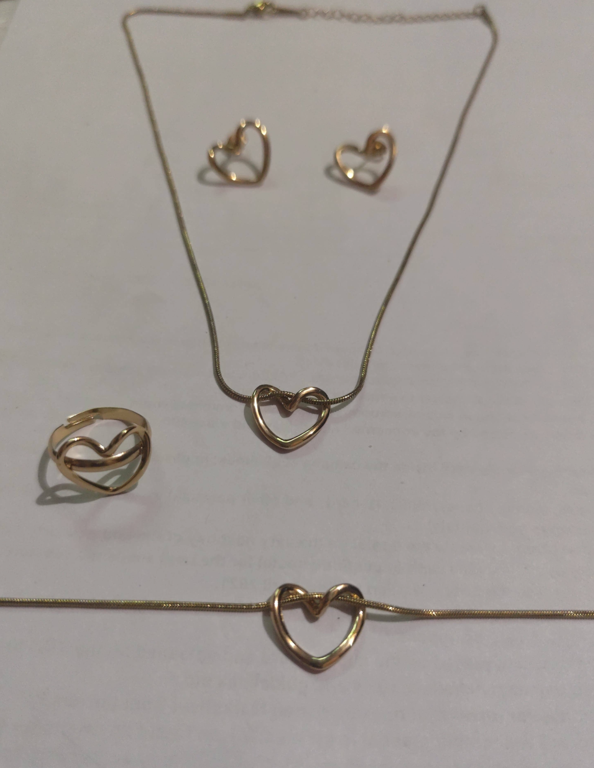 Gold heart knot jewelry set with necklace, earrings, ring, and bracelet