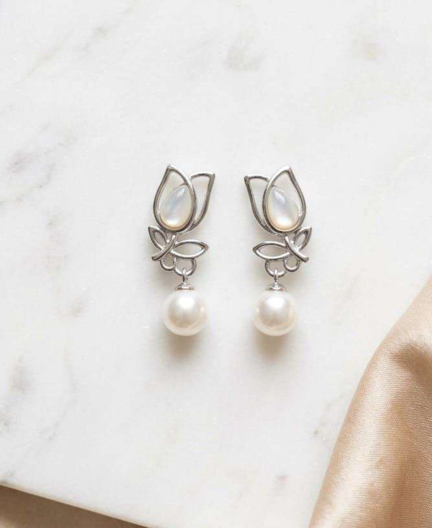 Silver-tone tulip drop earrings with mother-of-pearl inlay and dangling white pearl on marble surface