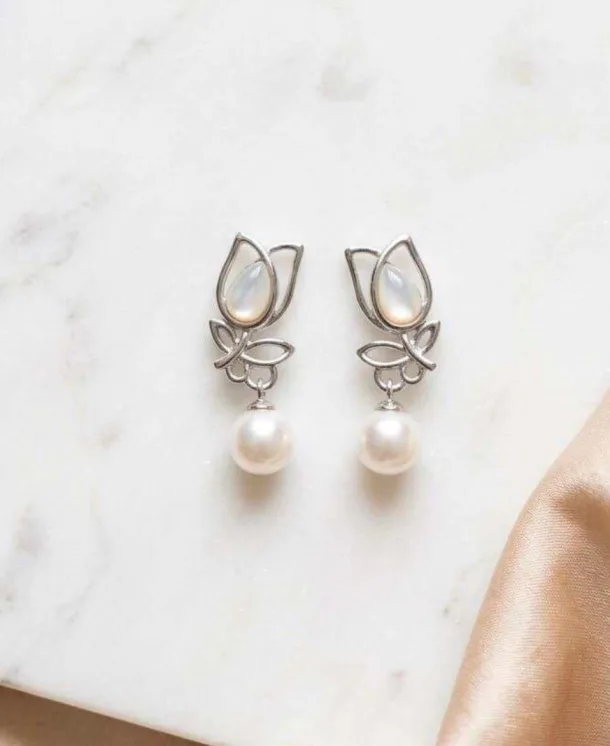 Silver-tone tulip drop earrings with mother-of-pearl inlay and dangling white pearl on marble surface